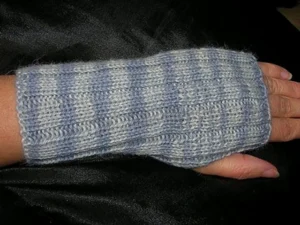 a ribbed fingerless mitt on the hand of a white person, The mitt has irregular stripes in two shades of grey