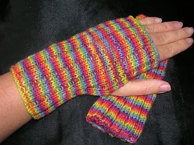 a ribbed fingerless mitt on the hand of a white person, The mitt has very thin stripes in rainbow colours