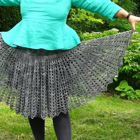cropped view of a person wearing a bright green top and a grey, lacy crochet skirt